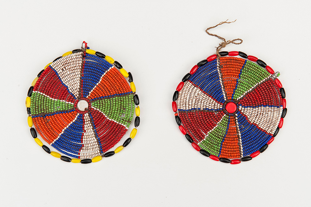 Two flat discs made of beads. Each disc is divided into slice-like segments of different colors, and bordered with two alternating colored beads.
