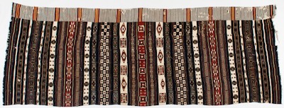 A patterned woven cloth comprised of cloth strips sewn together. Vertical bands of repeating geometric patterns appear in strips of varying widths and are made with combinations of white, blue, red-brown and black colors.