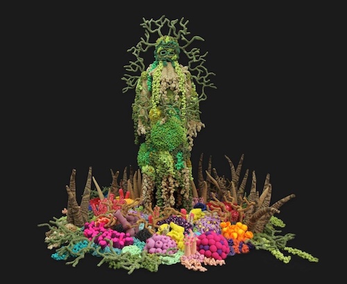 Figure covered in a green and brown coral-encrusted costume, standing amid colorful corals made of knit and crocheted yarn.