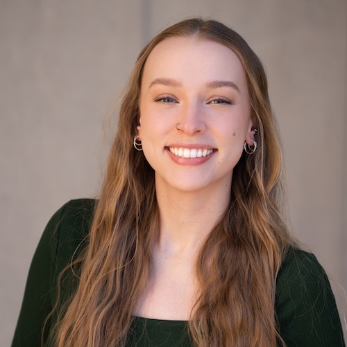 A black and white portrait of a light-skinned young woman with very long hair and a wide smile looking directly out at the viewer.