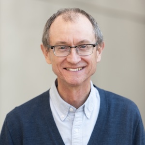 A smiling, gray-haired man with glasses smiles out at the camera.